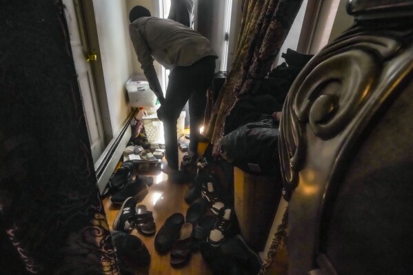 A migrant from Senegal searches through a delivery of city identification cards approved for African migrants at Bronx's Masjid Ansaru-Deen mosque, Friday March 15, 2024, in New York. (AP Photo/Bebeto Matthews)
